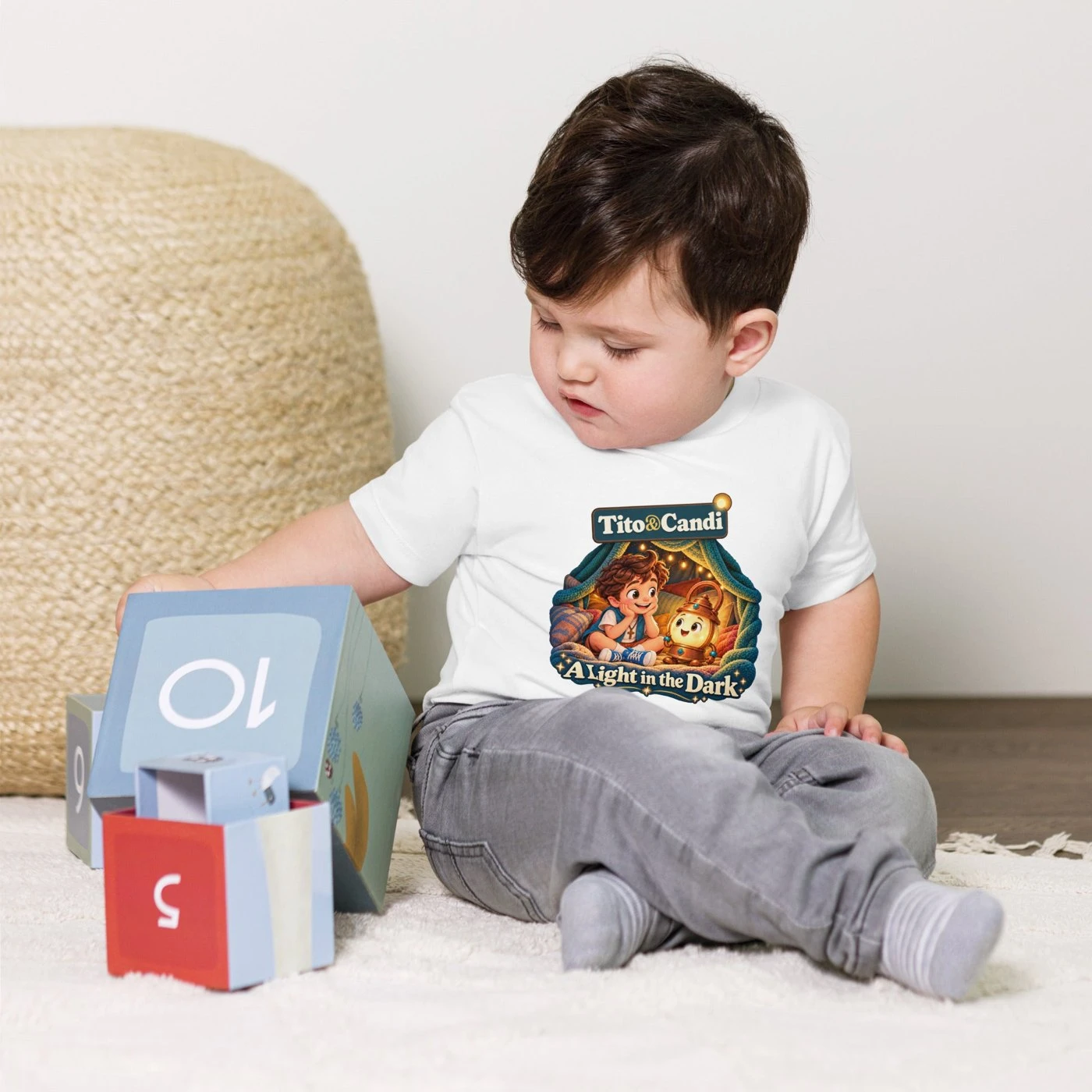Baby in a white T-shirt with the A Light in the Dark design showing Tito and a glowing Candi